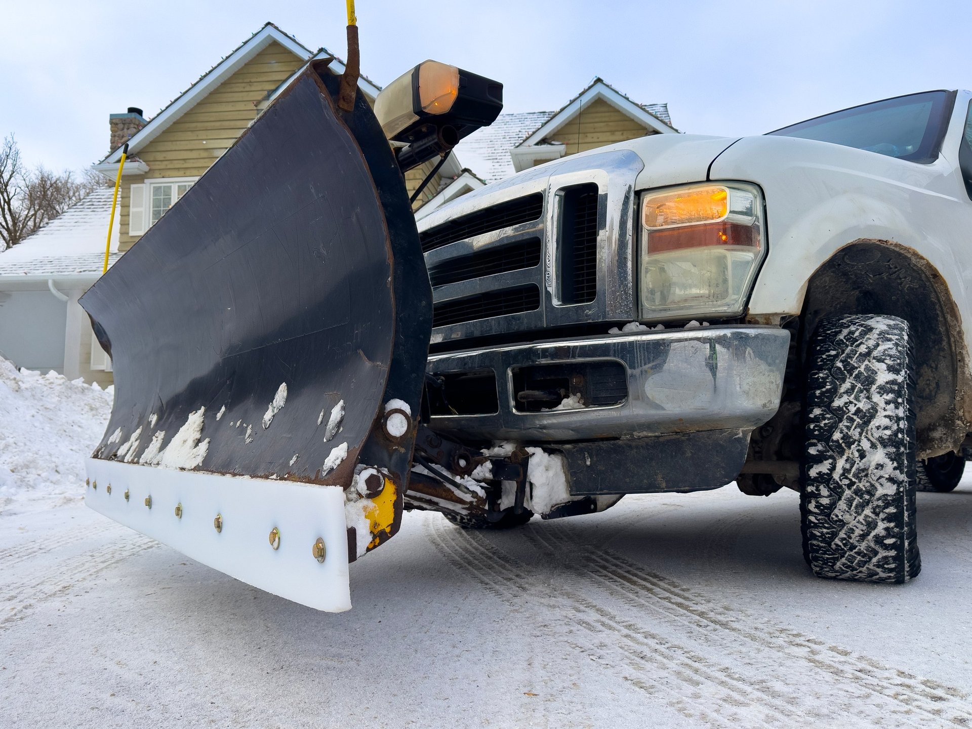 Front view of snow plow truck clearing snow on residential street after winter storm